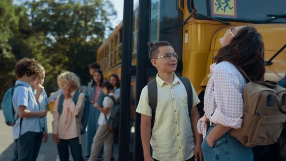 Two Pupils Stand Chatting at Schoolbus Waiting Bus Boarding alt