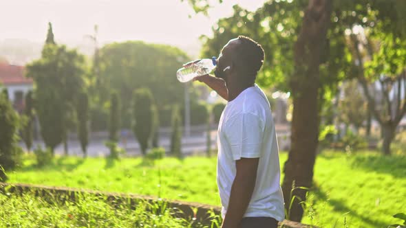 Young Adult Man in the Park Drinking Water