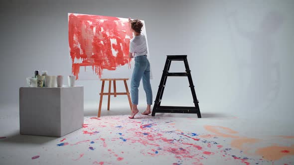 Back View Female Artist Draws with a Brush on a Large Canvas in a White Room a Talented Artist Draws alt