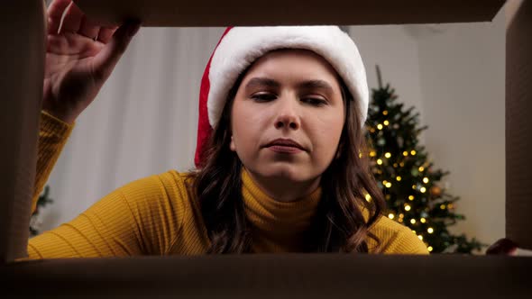 Inside Carton Box Smiling Woman in Santa Claus Hat Opens Christmas Box Upset alt