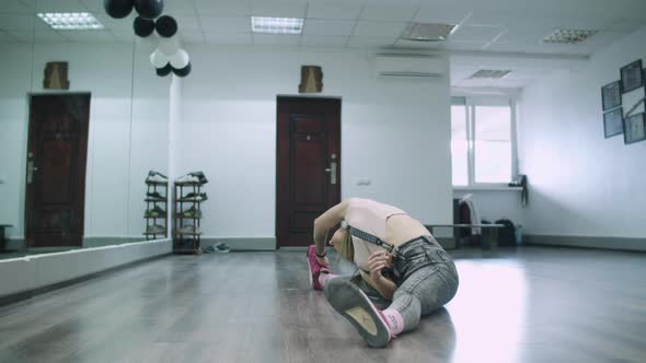 Caucasian female dancer choreographer stretching and warming up in the floor of a dance studio alt