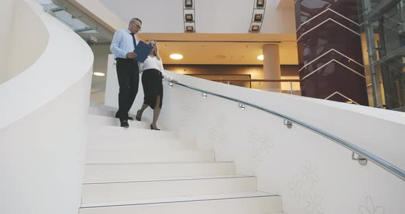 Business Partners Walking Downstairs in Office and Talking alt