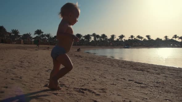 Active Little Boy Sunbathing on Beautiful Seaside. Sweet Child Playing at Beach. alt