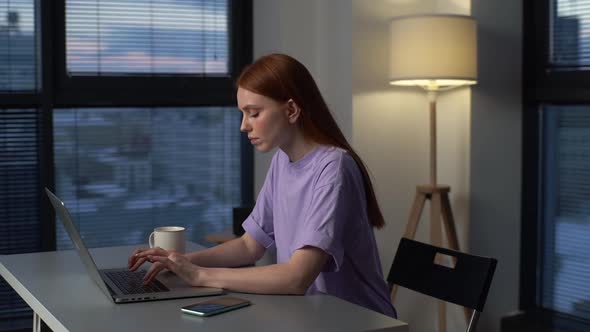 Overworked Redhead Young Woman Typing on Laptop Actively Feeling Pain in Wrist Sitting at Desk Near alt