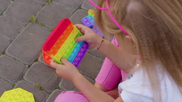 Child Girl Playing Colorful Squishy Silicone Bubbles Sensory Toy Simple Dimple Pop It Game Closeup alt