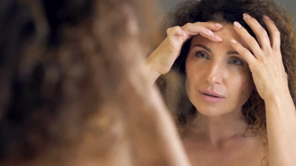 Beautiful Middleaged Woman Meticulously Examines Her Reflection in the Mirror alt