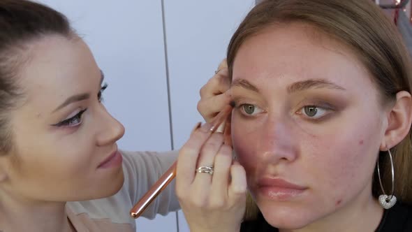 Eyeshadow are Applied with a Special Brush on the Eyelid of the Model alt