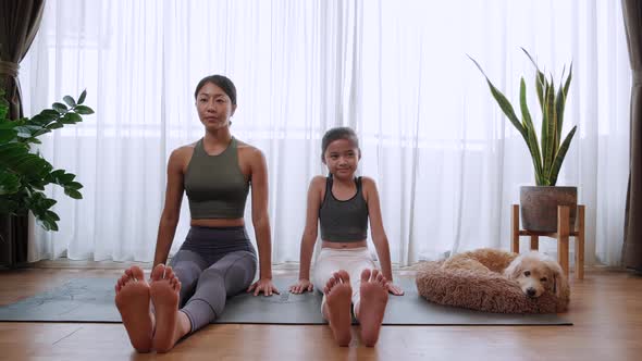 Mom and little daughter sitting on yoga mat for prepare to do yoga exercise at home