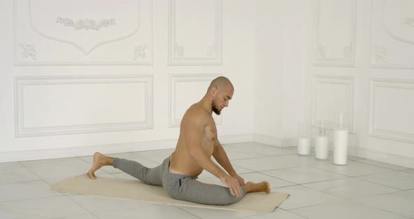 Man Is Stretching His Body and Practicing Yoga Poses in Light Hall in Daytime alt