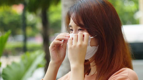Young asian woman wanting medical face mask standing on the street during virus pandemic