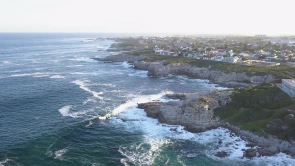Aerial over a rocky coastline and small town with waves breaking