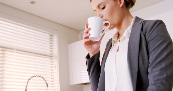 Woman drinking coffee in kitchen alt