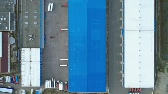 Aerial Top Down View of the Large Logistics Park with Warehouse with Some Semi-trailers Trucks. alt