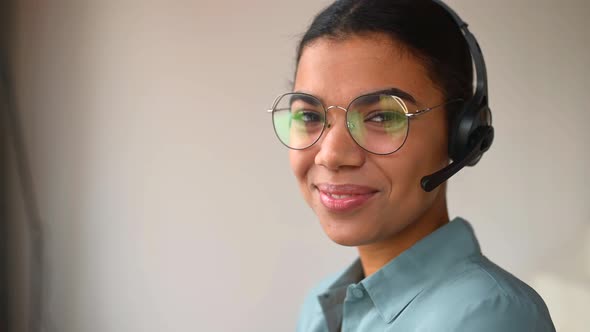 Headshot of Smiling Young Female Employee Wearing Wireless Headset Looking at Camera alt
