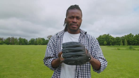 Portrait of Handsome Black Man in Baseball Glove Throwing Ball Outdoors alt
