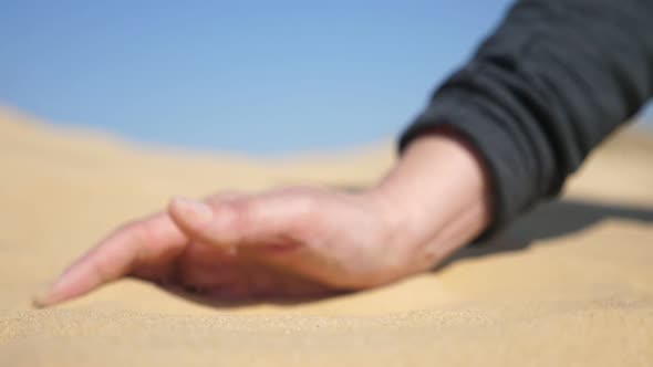Boy`s Hand Patting the Hot Grainy Sand on a Sunny Day in Spring in Slow Motion