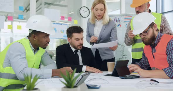 Multiethnic Group of Engineers Working Together Over joint Building Project alt