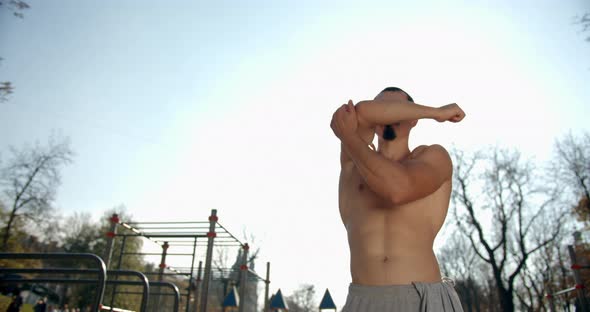 Man Is Doing Hand Warm-up Before Training on the Sport Area in Good Weather  alt