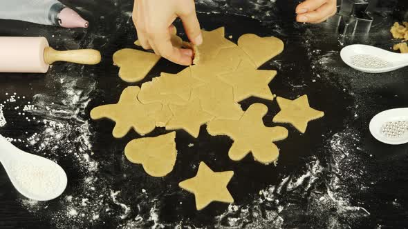 Female hands make gingerbread cookies in different shapes from rolled dough  alt
