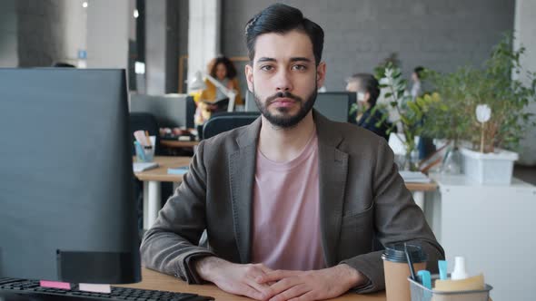 Slow Motion Portrait of Mixed Race Businessman Sitting at Desk with Computer in Coworking Office alt