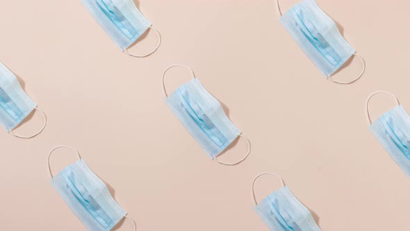 Pattern of Blue Medical Masks on a Pastel Pink Background Slow Motion alt