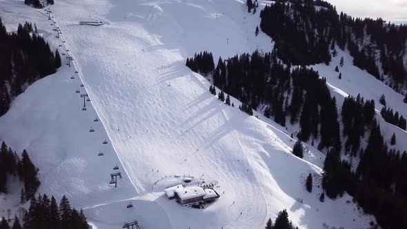 Aerial view smoothement along the ski slopes in the ski resort. Magnificent snowy mountains and blue alt