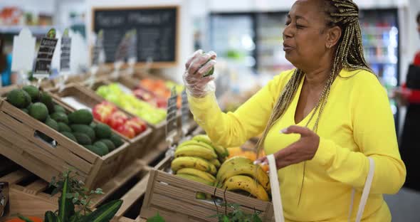 African female customer buying organic food fruits inside eco fresh market - Shopping concept alt