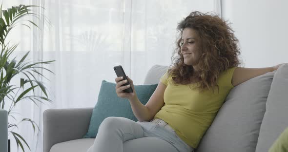 Woman sitting on the couch and using her smartphone