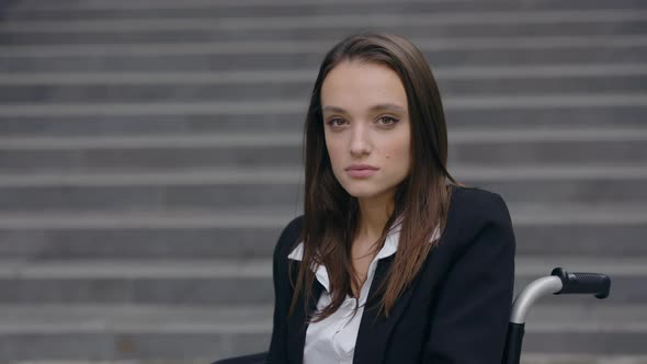 Close Up View of Businesswoman Invalid in Formal Suit Sitting in Wheelchair at Street alt