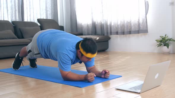 Overweight Man Struggling To Do Plank While Watching Online Tutorial On Laptop alt