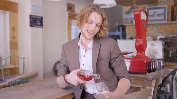 Male sommelier pouring fruit wine at a bar alt