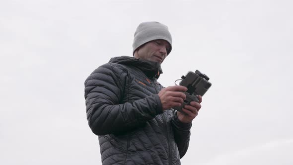 Photographer Using Remote Control Handset To Control Drone alt