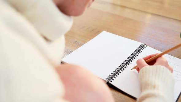 Close-up of woman writing in organizer while having coffee 4k alt