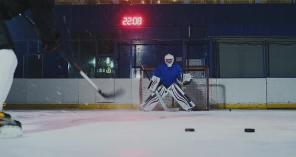 Close-up of a Hockey Puck in Slow Motion and a Putter of Several Pucks in Turn and a Goalkeeper in alt