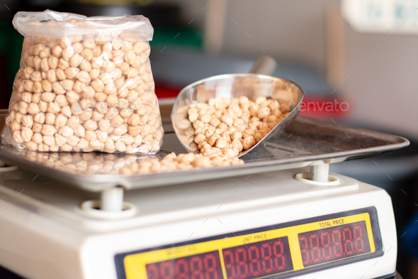 Fresh chickpeas on the weighing scale. Chickpeas watered in bag and metal shovel.
