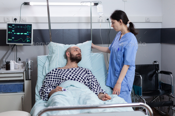 Nurse fixing pillow taking care of patient with respiratory insufficiency connected to monitor - Stock Photo - Images