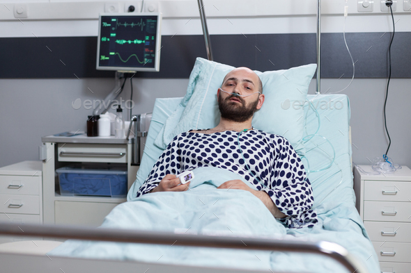Patient lying in hospital bed with respiratory problems connected to monitor measuring vitals