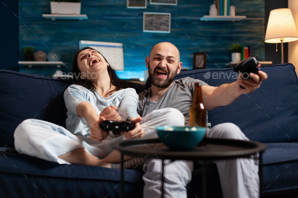 Focused determined couple playing soccer video game late night