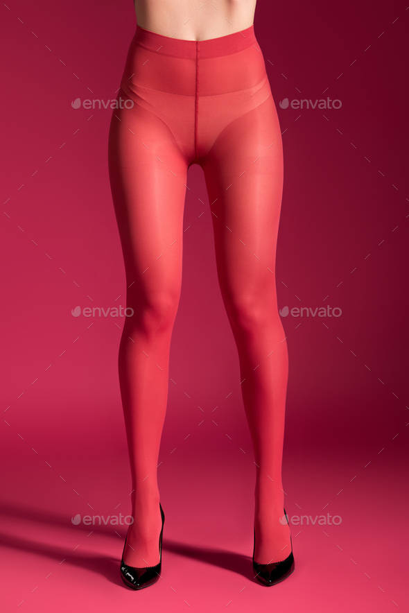 Female thin legs in red nylon tights on red background Stock Photo