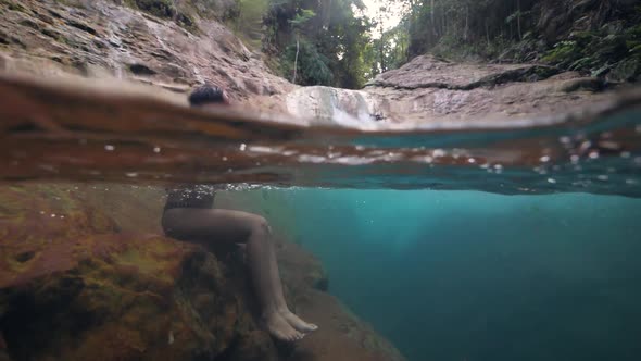 Pretty Young Woman Sitting at Pristine Waterfall Stream in the Forest alt