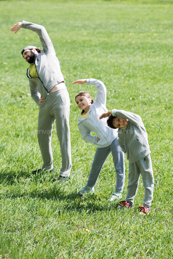 happy sportive family doing physical exercise on grass