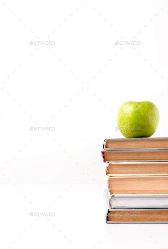 Cropped view of stack of books with apple on top isolated on white