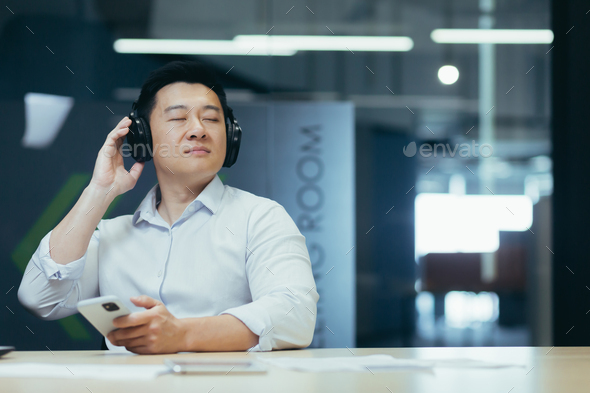 Asian boss business owner relaxing in office, listening relaxing and relaxing music