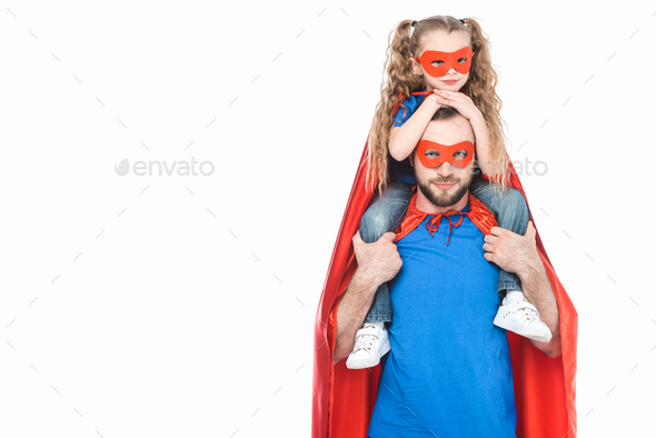 super father carrying little daughter in mask and cloak and looking at camera isolated on white
