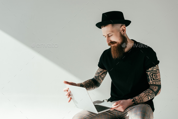 handsome bearded tattooed man working with laptop on white Stock Photo by  LightFieldStudios