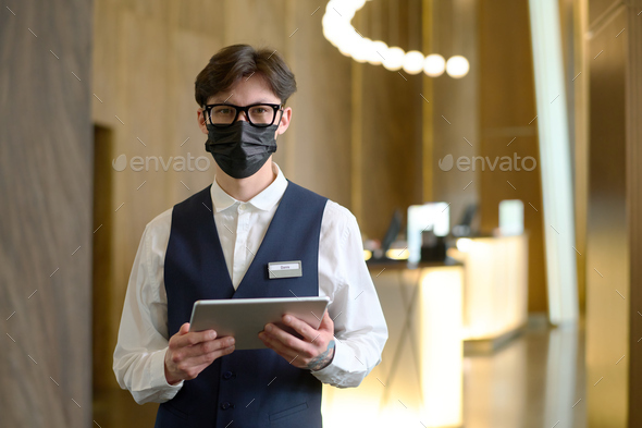 Young owner of luxurious hotel with digital tablet looking at camera - Stock Photo - Images