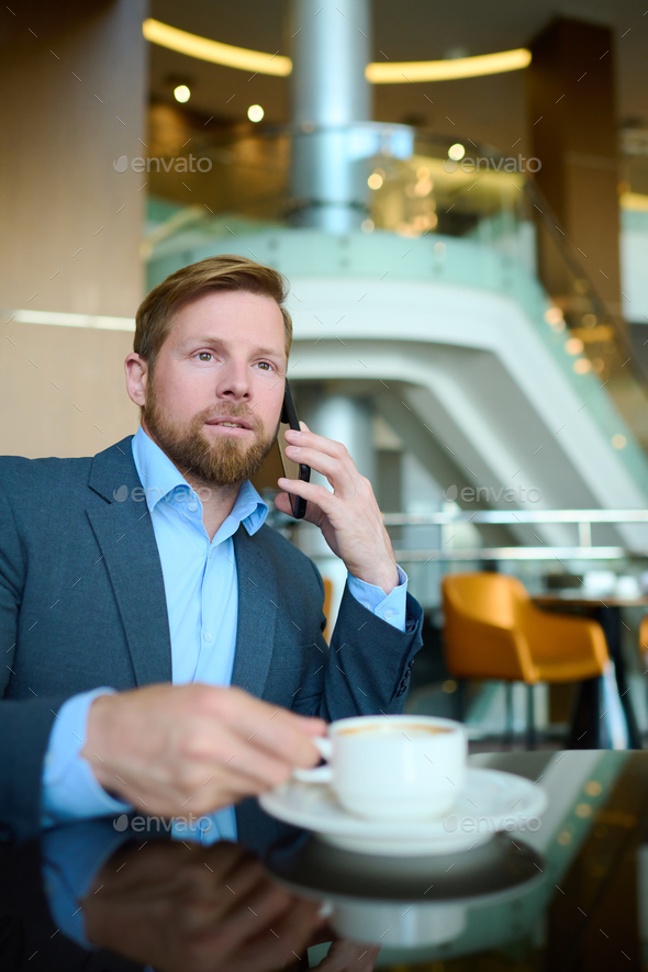 Young businessman with smartphone by ear communicating with partners
