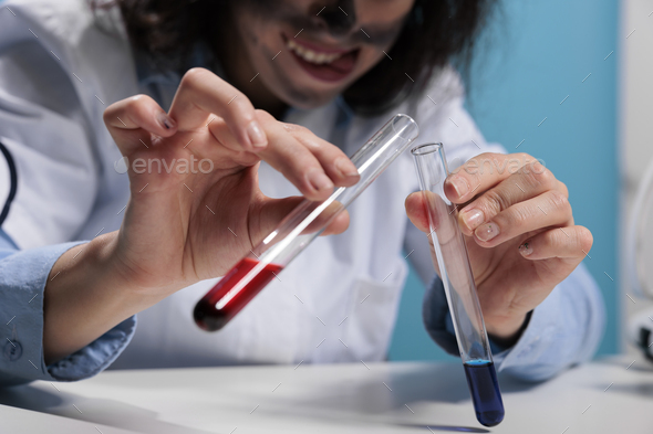 Close up of mad scientist hands mixing experimental liquid chemical compounds after laboratory