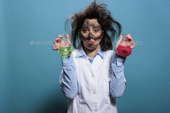 Sad lunatic chemist holding glass flasks filled with unidentified toxic chemical compounds.