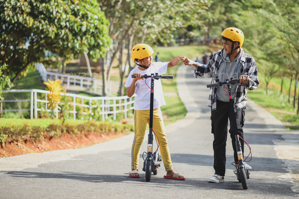 Young scooter riders doing fist bumps
